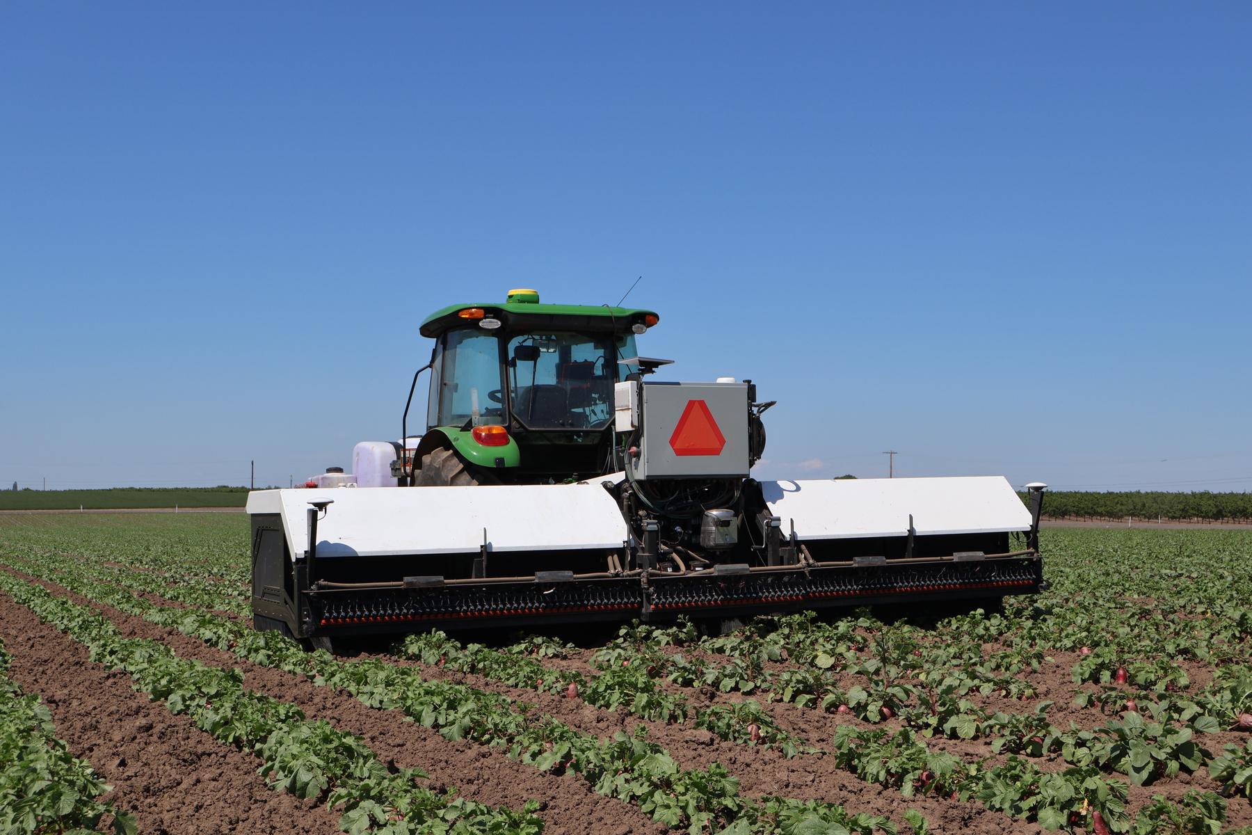 Atlas working a specialty crop field with teams walking the rows.